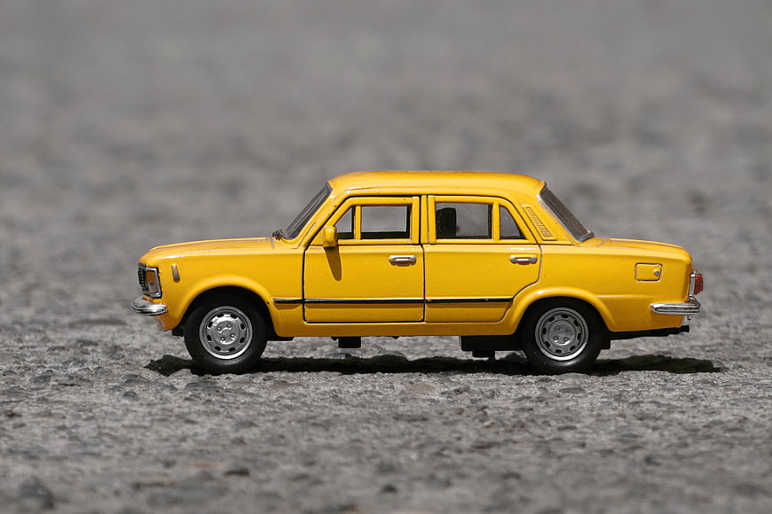 Yellow Fiat 125p Toy Car on Gravel Surface