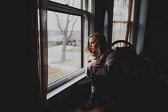 Sad woman sitting by window looking down