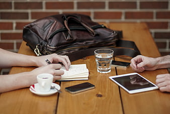 Business meeting with coffee, tablet, and notebook on wooden table