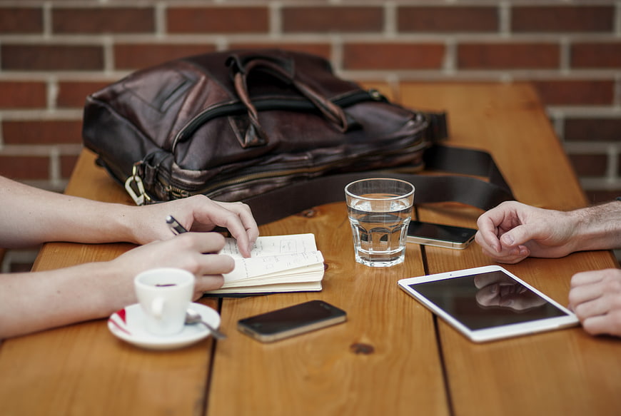 Business meeting with coffee, tablet, and notebook on wooden table