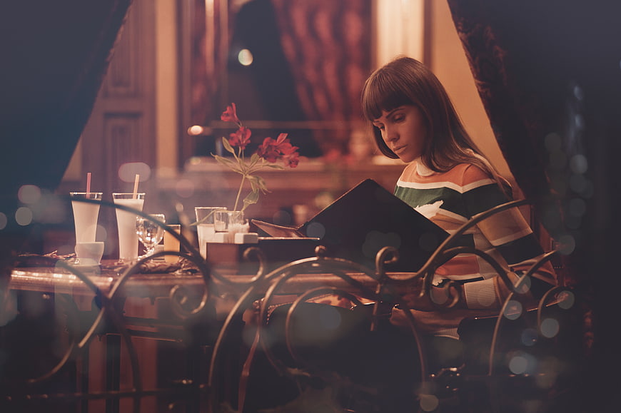 Woman reading menu at restaurant table at night