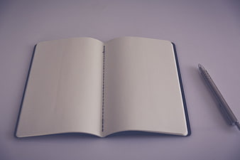 Open blank notebook with pen on purple background