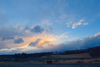 Dramatic sunset clouds over rural farmland landscape
