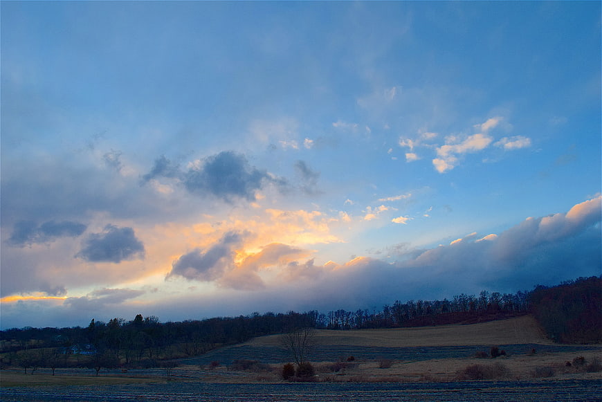 Dramatic sunset clouds over rural farmland landscape