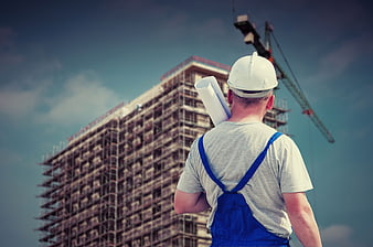 Construction worker with blueprints looking at building site