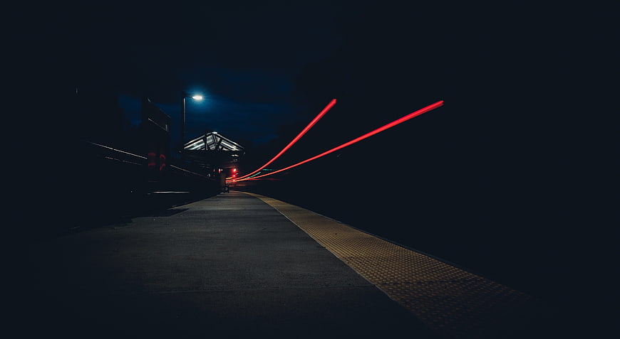 Long Exposure Red Light Trails on Dark Train Platform at Night