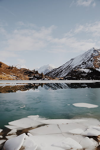 Frozen Alpine Lake with Snow-Capped Mountain Reflections