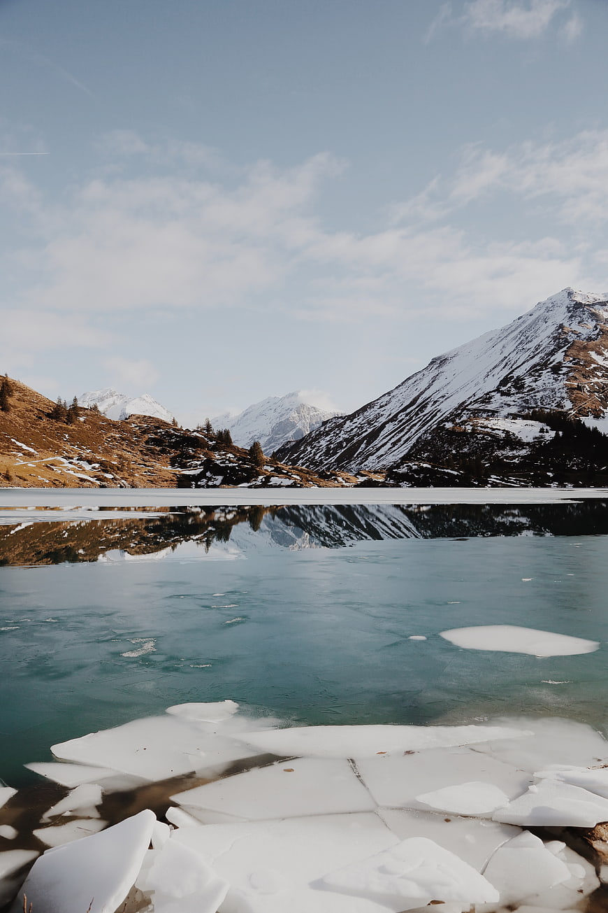 Frozen Alpine Lake with Snow-Capped Mountain Reflections