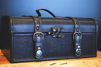 Vintage Black Leather Trunk on Wooden Surface