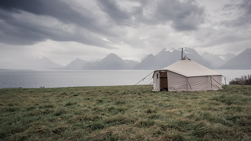 Glamping Tent by Fjord with Mountains and Cloudy Sky