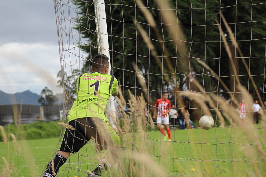 Soccer Goalkeeper in Action Behind Net