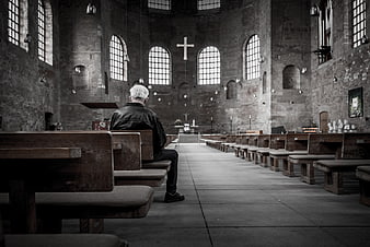 Senior man praying alone in rustic stone church interior
