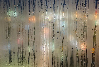 Raindrops on glass with blurred city lights background