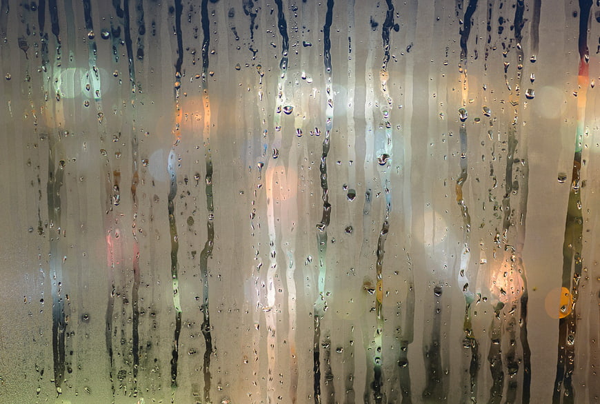 Raindrops on glass with blurred city lights background