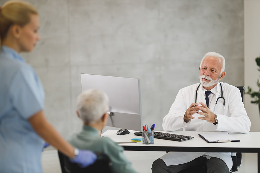 Senior Doctor Consulting with Elderly Patient in Wheelchair