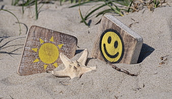 Hand-painted wooden blocks with sun and smiley face on sandy beach