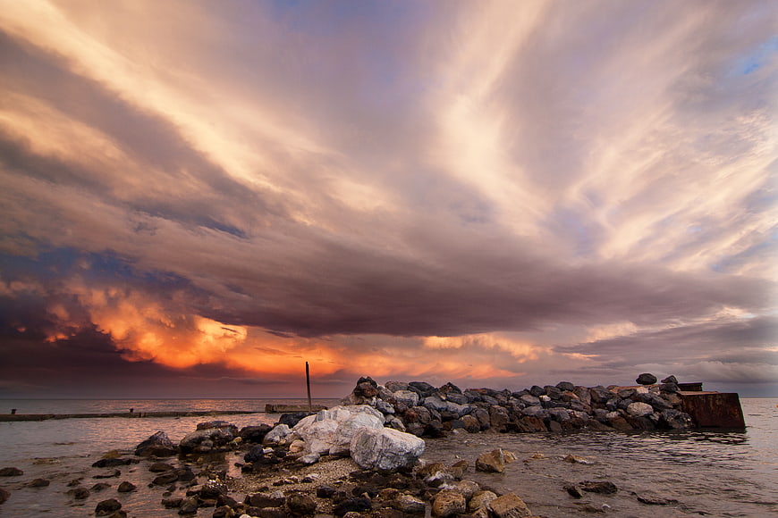 Dramatic Sunset Over Rocky Jetty and Ocean
