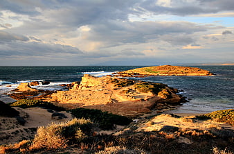 Dramatic Rocky Coastline with Golden Hour Sunlight and Waves