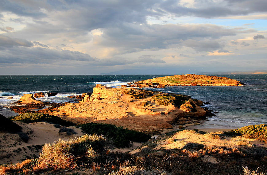 Dramatic Rocky Coastline with Golden Hour Sunlight and Waves