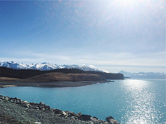 Scenic turquoise lake with snow-capped mountains and rocky shore