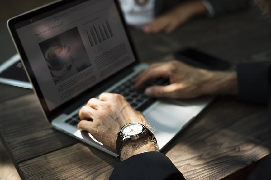 Man Typing on Laptop with Business Charts on Screen