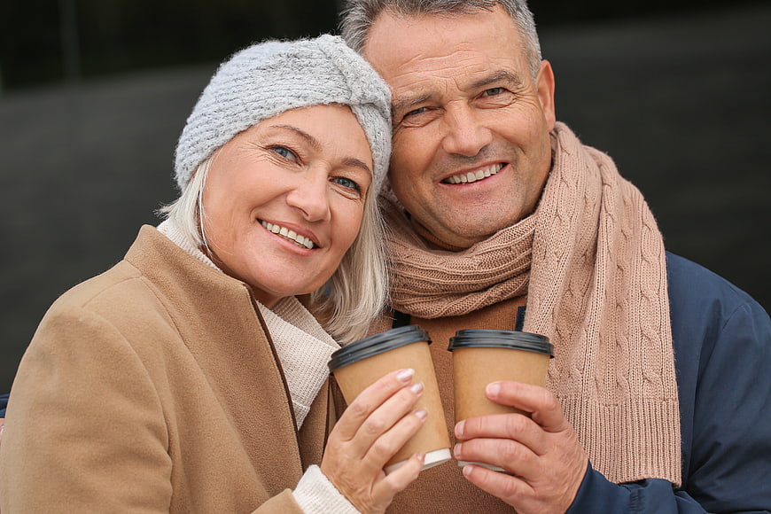 Happy senior couple holding coffee cups outdoors