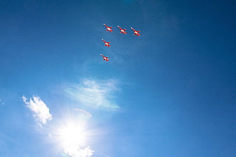 Red Jet Formation Flying in Blue Sky with Sun