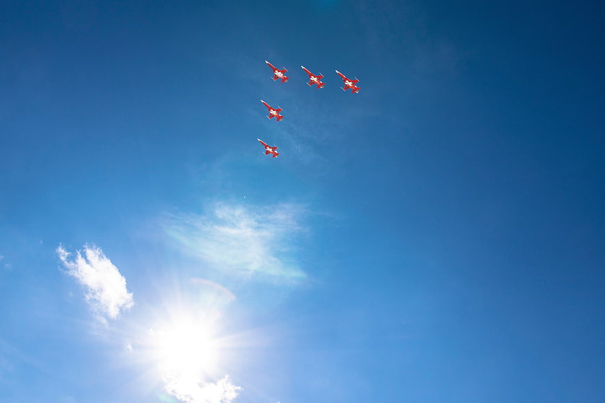 Red Jet Formation Flying in Blue Sky with Sun