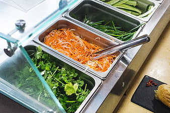 Fresh vegetables in metal trays for sandwich preparation