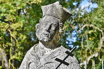 Weathered Stone Statue of a Religious Figure with Cross
