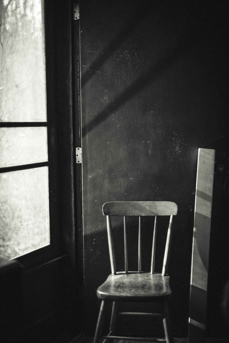 Vintage wooden chair in dark room with window light