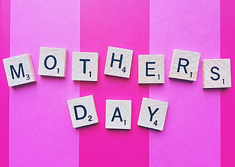 Scrabble tiles spelling Mother's Day on pink striped background