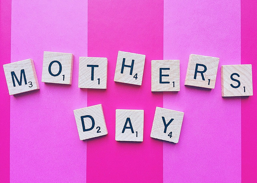 Scrabble tiles spelling Mother's Day on pink striped background