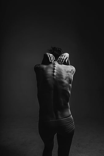 Black and white photo of a man's back with hands on neck