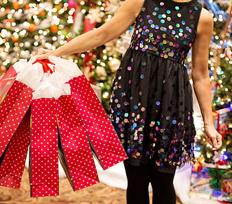 Woman holding red polka dot gift bags in festive Christmas store