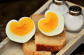 Heart-shaped boiled eggs on toast with salt shakers