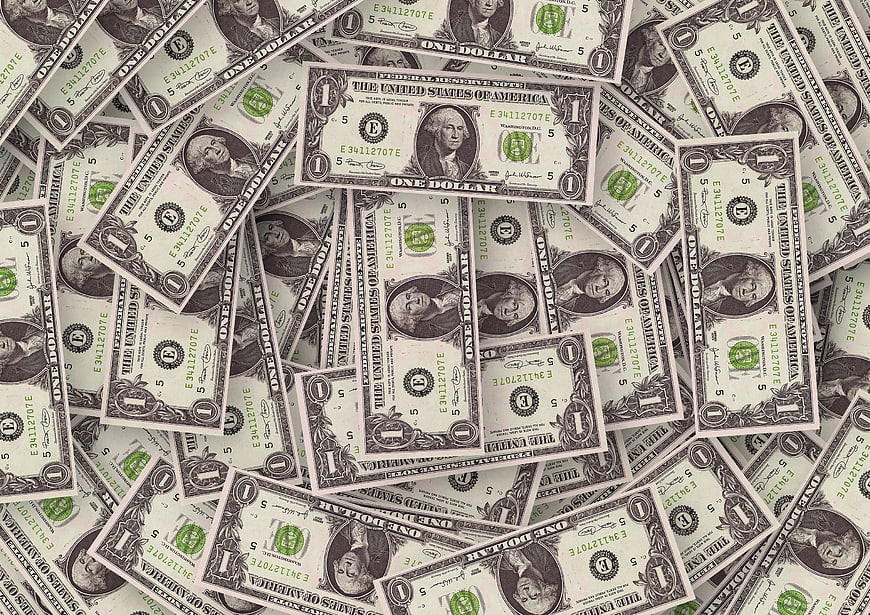 Scattered US One Dollar Bills Covering Surface