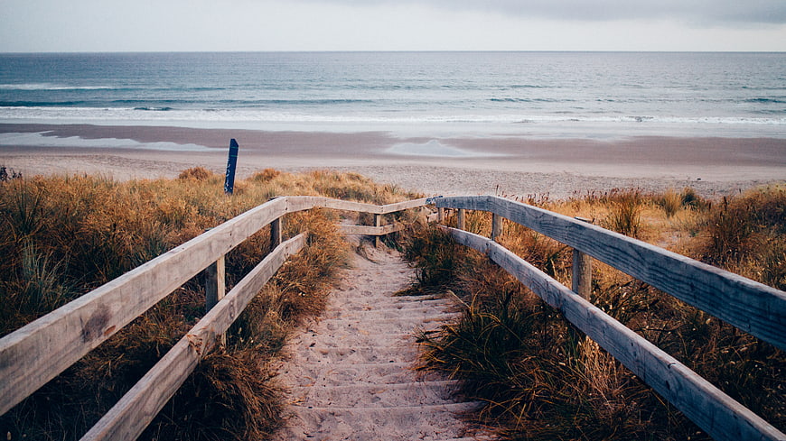 Wooden stairs leading to sandy beach with ocean view