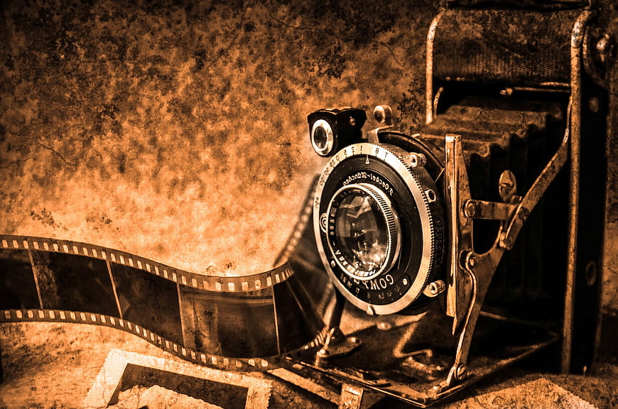 Vintage folding camera with film strip on textured background