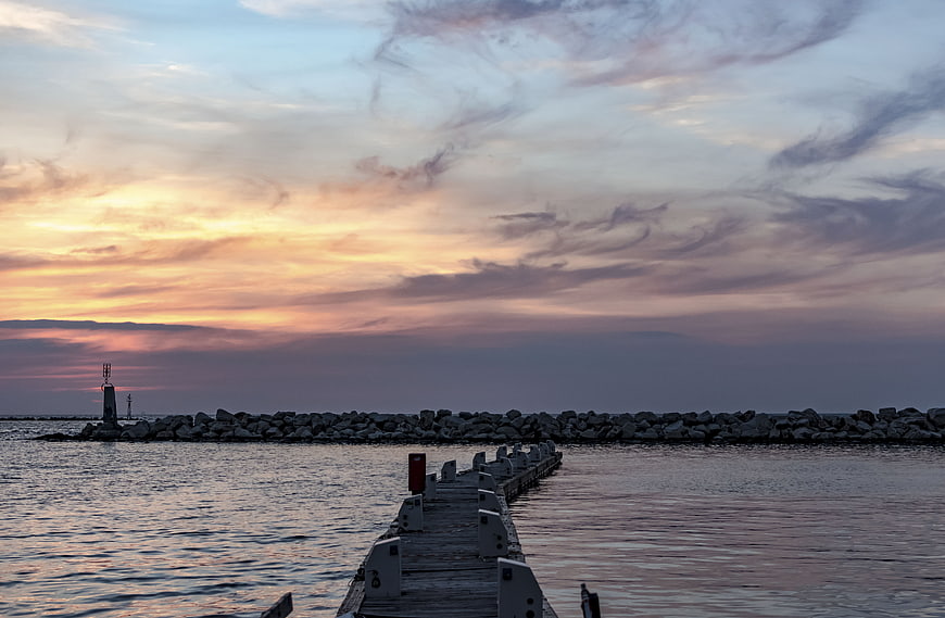 Sunset over a wooden pier and rocky breakwater