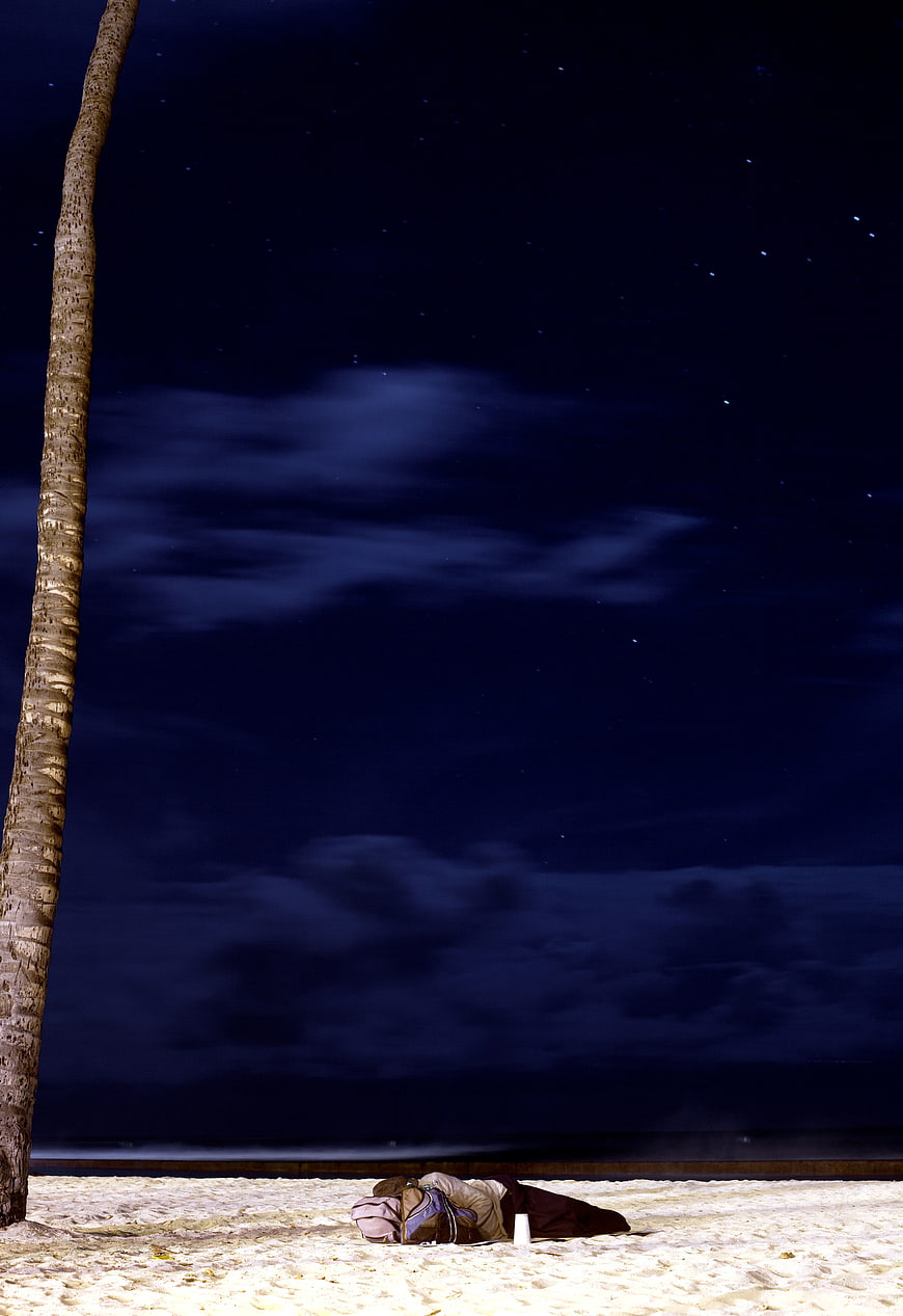 Person Sleeping on Sandy Beach Under Starry Night Sky