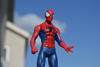Spider-Man Action Figure Toy Standing Outdoors Against Blue Sky