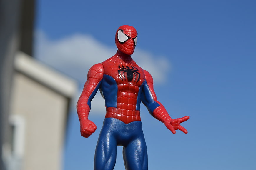 Spider-Man Action Figure Toy Standing Outdoors Against Blue Sky