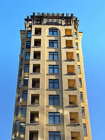 Tall beige apartment building facade against blue sky