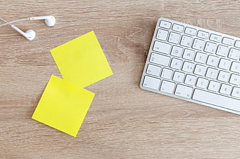 Flat lay of workspace with keyboard, sticky notes, and earphones