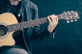 Musician playing acoustic guitar in leather jacket