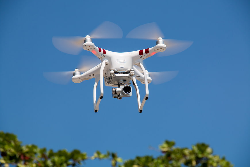 White Quadcopter Drone Flying Against Blue Sky
