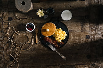 Rustic breakfast with pancakes, bacon, and eggs on wooden table