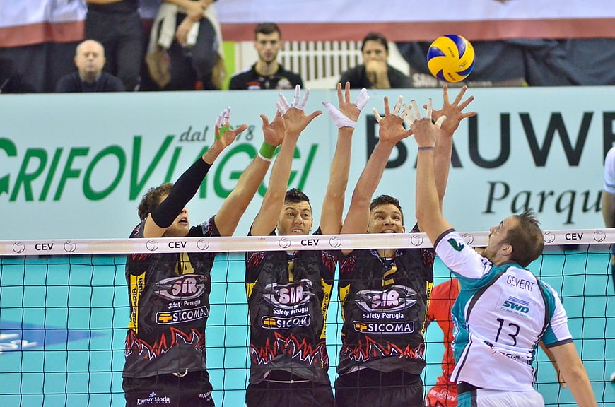 Volleyball players blocking the ball at the net