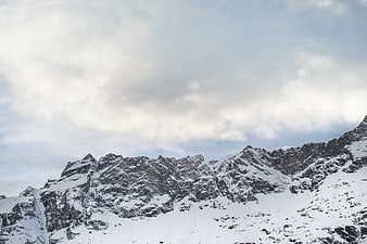 Snowy mountain peaks under cloudy winter sky